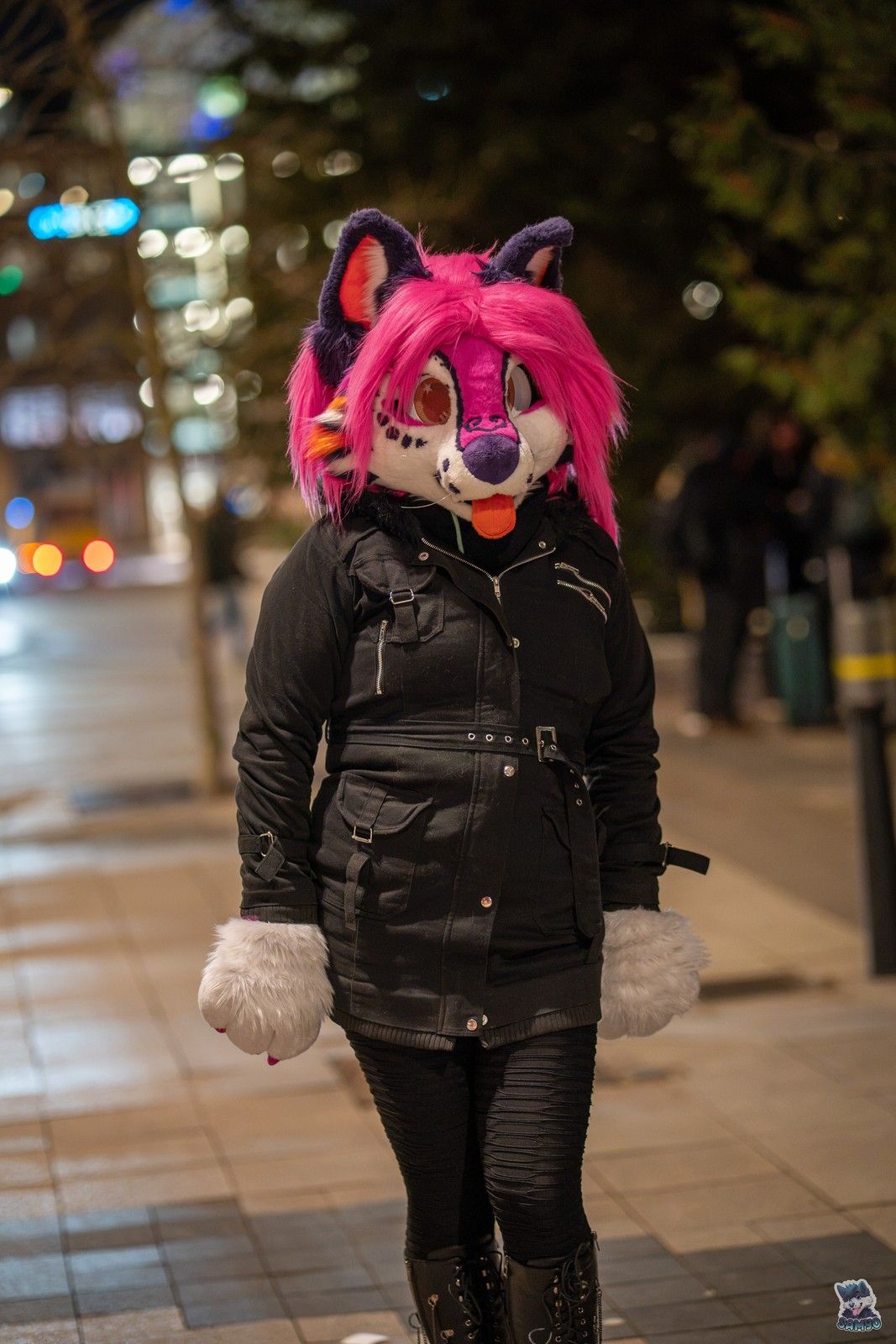 Peechy in a black coat on a city street at night